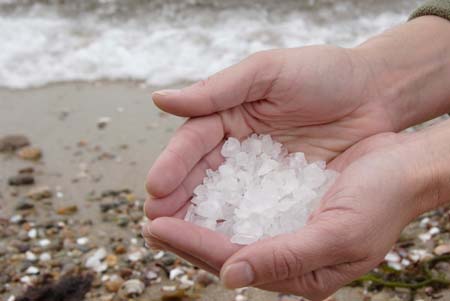 Cupped hands holding salt crystals by the sea