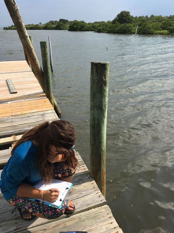 Juliana Navarro on a dock collecting data on mangroves